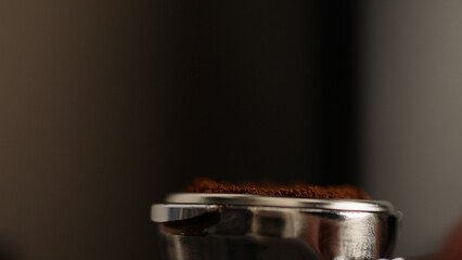closeup of tamping fresh ground coffee in portafilter