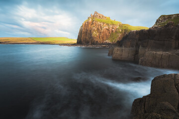 Dramatic seascape and landscape at sunset or sunrise of the historic castle ruins of Duntulm Castle on the Isle of Skye coast in the Scottish Highlands, Scotland.