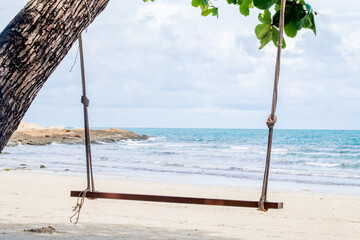 Wooden swing hanging from a tree on the beach.swinging swing on the river bank in the setting sun, concept time to travel in vacation
