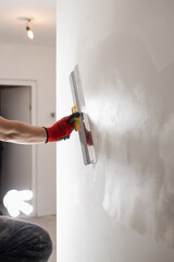 Leveling the wall surface with white putty and a spatula is the work of a qualified painter and finisher