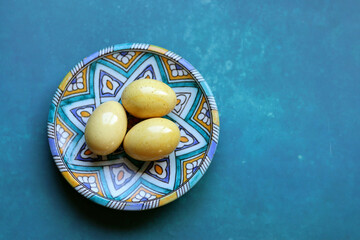 Easter eggs on a turquoise ceramic plate, textured background with copy space. 