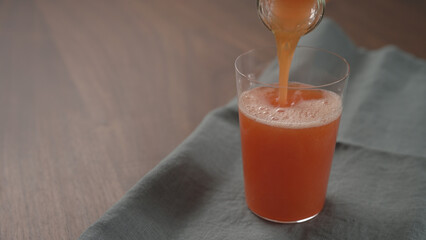 pour red orange drink into tumbler glass with copy space