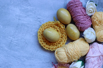 Easter background. Easter eggs, ribbons, flowers and crochets on a gray background.