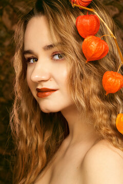 Girl with fesalis. A girl and a natural bouquet of orange dried flowers. Side view of the girl. A girl with a branch of fesalis flowers in her hair.