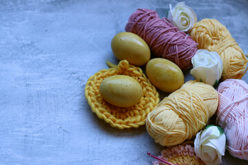 Easter eggs and cotton yarn threads on textured background with copy space. Easter decoration. 