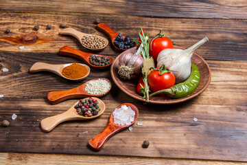 Many different spices and vegetables on a wooden table, aromatic spices and fresh vegetables for...