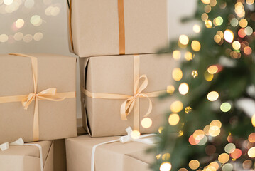 Christmas home interior. Boxes with gifts. Christmas tree with garland lights is blurred in the background. Holiday decor.