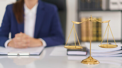 Lawyer woman working about business contract and legal agreement with brass balance scales on desk