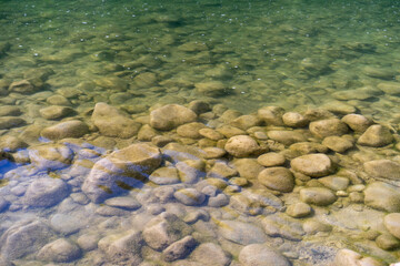 flowing water in a calm river where there are rocks in the water. River water surface details, reflections and abstracts, ripples and patterns.