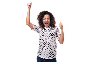 young stylish woman with curly hair dressed in a blouse with polka dots smiles and feels happy