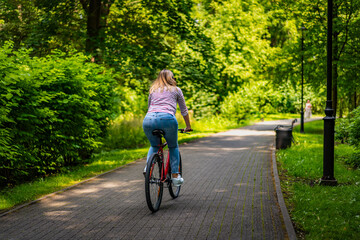Obraz premium Woman riding bicycle in city park 