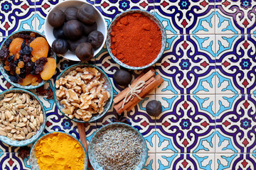 Spices and herbs in bowls on traditional Moroccan blue tiles background. 