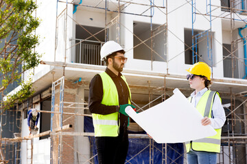 Engineers and Architect Caucasian looking at blueprint of building construction, planning the work in a professional. inspector is looking at steel structure and materials at construction site.