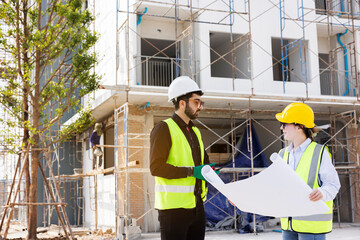 Engineers and Architect Caucasian looking at blueprint of building construction, planning the work in a professional. inspector is looking at steel structure and materials at construction site.