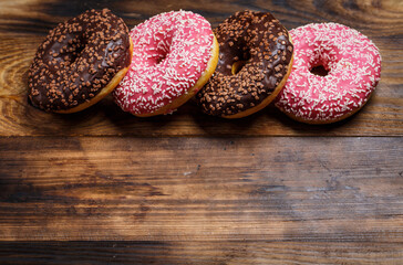 Chocolate and pink sweet donut on wooden table, breakfast donut
