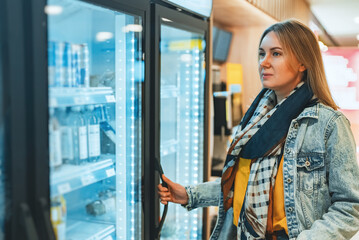 Woman buys water from the refrigerator in a store.