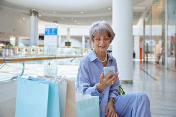 Attractive elderly woman using mobile phone in shopping mall