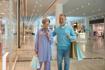 Overjoyed senior couple with shopping bags rejoicing successful purchases