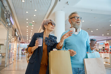 Fashionable elderly couple enjoying shopping tour on black friday weekends
