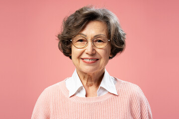 Smiling beautiful senior woman, grandmother, wearing eyeglasses, looking at camera standing...