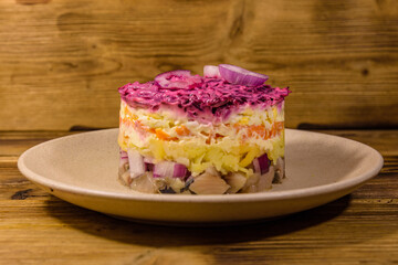 Ceramic plate with russian traditional new year salad herring under fur coat (shuba) and on rustic wooden table