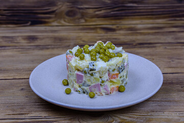 Ceramic plate with new year salad olivier on a wooden table