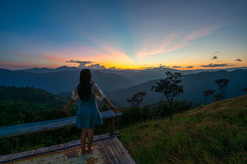A woman stands admiring the mountain view at sunset at Huai kup kap village, Chiang mai, Thailand.