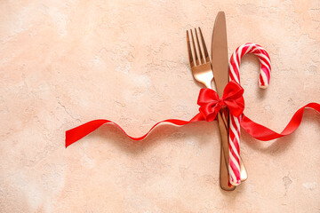 Cutlery and candy cane tied with red ribbon on beige grunge background