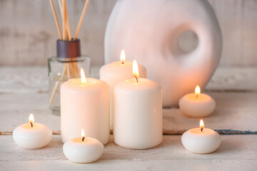 Burning candles on white wooden background