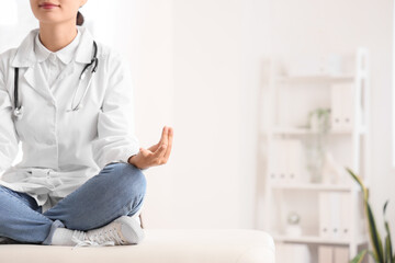 Female doctor meditating on couch in clinic