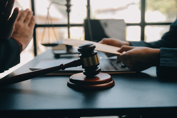 Justice and law concept.Male judge in a courtroom with the gavel, working with, computer and docking keyboard, eyeglasses, on table in morning light