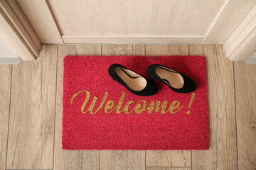Welcome doormat with shoes in hall, top view