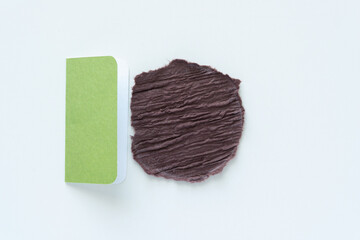 rough circle with torn edges in textured brown paper and folded green card on blank paper