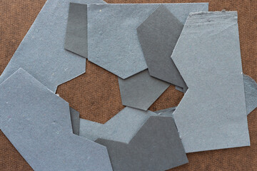 pile of cut gray paper shapes with zigzag edges on board