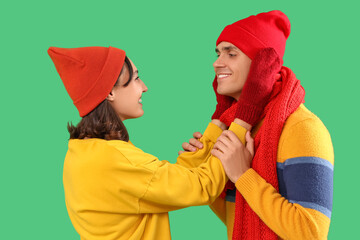 Happy young couple in warm clothes on green background