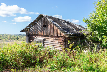 Abandoned destroyed rural wooden house in russian village in summer sunny day