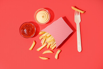 Paper box with french fries, ketchup and mayonnaise on red background