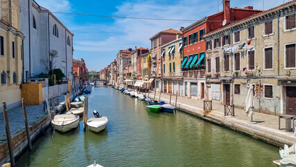 Panoramic view of a water channel in city of Venice, Veneto, Italy, Europe. Venetian architectural landmarks and old houses facades along the man made water traffic corridor. Urban tourism in summer