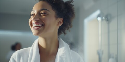 A woman in a bathrobe smiles as she brushes her teeth. This image can be used to promote dental hygiene or morning routines