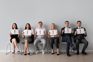 Applicants holding paper sheets with exclamation marks near light wall