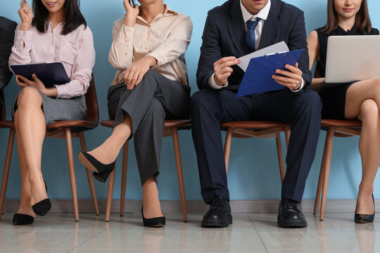 Applicants waiting for job interview near blue wall