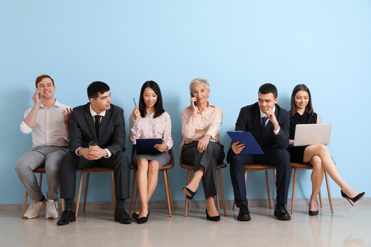 Applicants waiting for job interview near blue wall