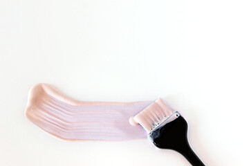 Hair coloring brush with a smear of light paint on a white background.