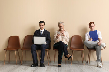 Applicants waiting for job interview near beige wall