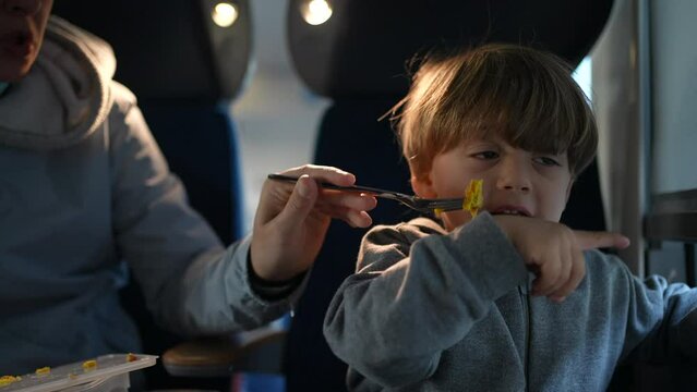 Mother Feeding Child on Train, Son Eating During Journey. Family traveling in high-speed transportation in Europe