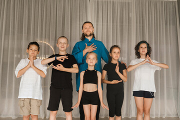 A joint portrait of a yoga coach and children standing in a fitness room