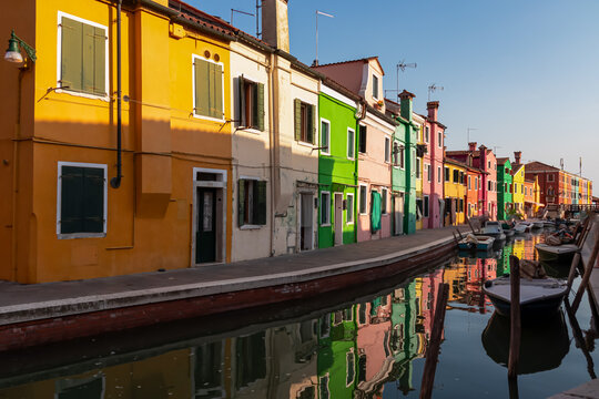 Scenic view of bright colorful houses on island of Burano in city of Venice, Veneto, Northern Italy, Europe. Cruising around the Venetian Lagoon. Water canal along idyllic riverbank. Summer tourism