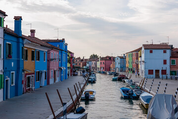 Fototapeta na wymiar Scenic view of bright colorful houses on island of Burano in city of Venice, Veneto, Northern Italy, Europe. Cruising around the Venetian Lagoon. Water canal along idyllic riverbank. Summer tourism