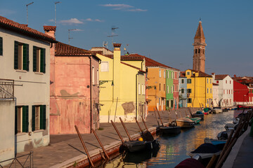 Fototapeta na wymiar Scenic view of bright colorful houses on island of Burano in city of Venice, Veneto, Northern Italy, Europe. Cruisingin the Venetian Lagoon. Leaning bell tower Il Campanile Storto at end of channel