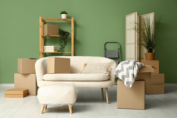 Sofa with cardboard boxes and pouf in living room on moving day